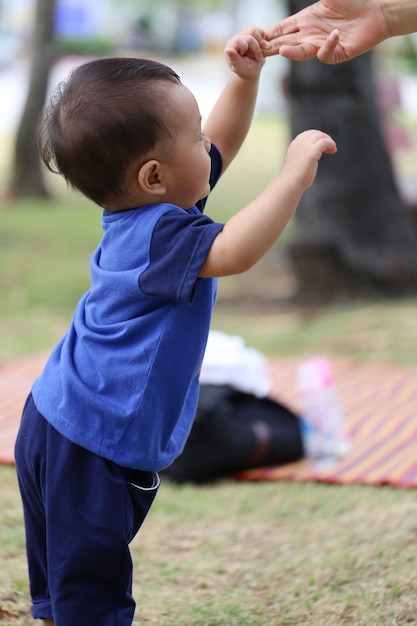 アジアの少年は庭を歩くことを学んでいます。