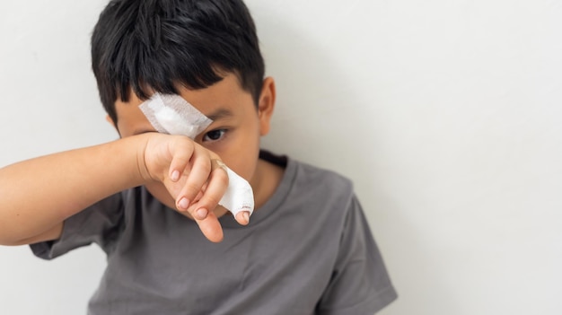 Photo asian boy is sad he had wound on face and fingers asian kid boy was accident injured while playing isolated on white background life insurance