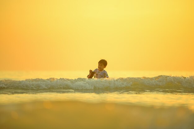 写真 海の近くの砂浜で遊ぶアジアの少年