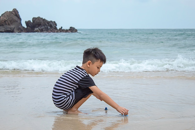 Ragazzo asiatico che gioca giocattolo su una spiaggia del mare.