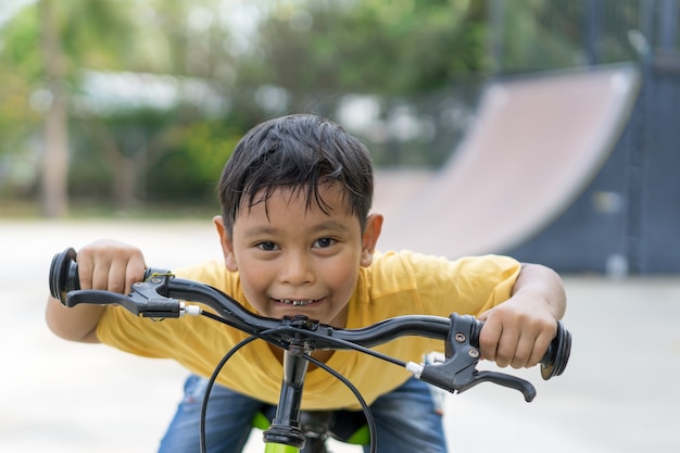 公共の公園でアジアの少年に乗って自転車