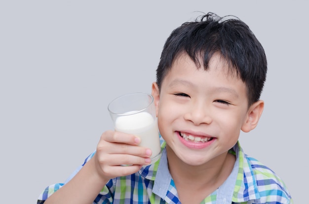 Photo asian boy smiles and holding a glass of milk