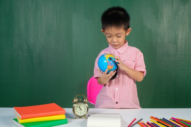 アジアの男の子、笑顔とチョークボードルームで学ぶ