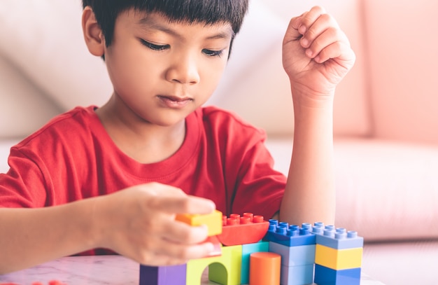 テーブルの上のおもちゃのブロックを積み重ねるアジアの少年