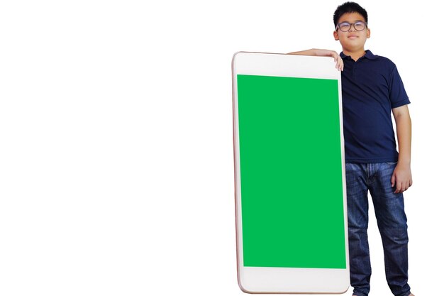 Asian boy stand near big mobile phone with blank screen workspace area on white background.