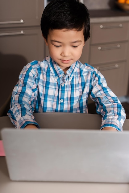 검역 기간 동안 집에서 노트북으로 온라인으로 공부하는 아시아 소년