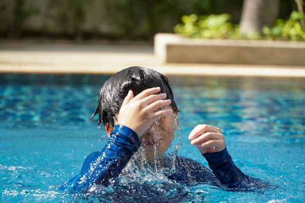 Asian boy swimming happily in the pool