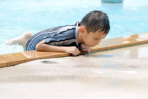 水着でアジアの少年、プールで楽しい遊泳。