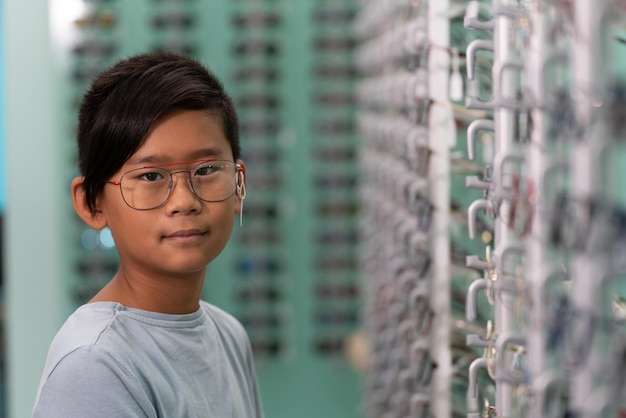 An asian boy trying on glasses in an optician store Background with glasses showcase