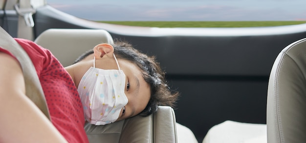 Asian boy wear protet mask from coronavirus covid 19 epidermic in car while travel new normal