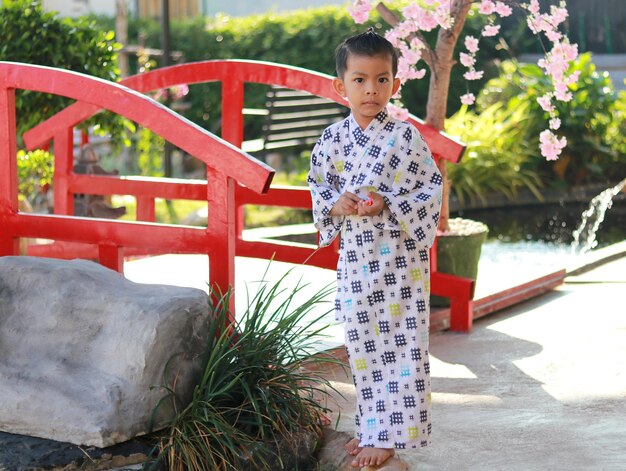 Photo asian boy wearing uniform japan background bamboo fence mountain view  light sunlight nature evening