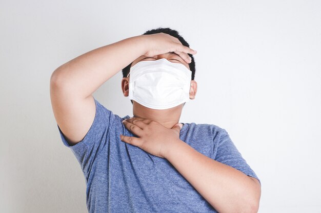 Азиатский мальчик носит маску, закрывающую рот и нос, предотвращающую коронавирус.