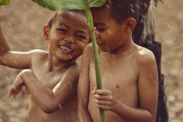 Foto i ragazzi asiatici sono felici perché giocano sotto la pioggia. dopo una lunga siccità