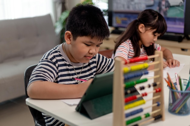 asian boys and girls enjoy online learning by taking notes and using tablets at home