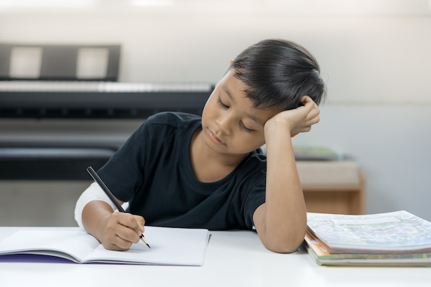 Un ragazzo asiatico alle mani ferite stanco di scrivere un quaderno