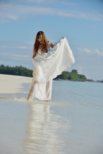 азиатская невеста с вуалью на пляже в небе и синем море. медовый месяц на фантастическом острове летом