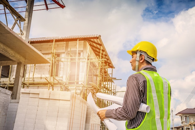 Asian business man construction engineer worker in protective helmet and blueprints paper on hand at house building site