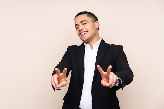 Asian business man isolated on beige background smiling and showing victory sign