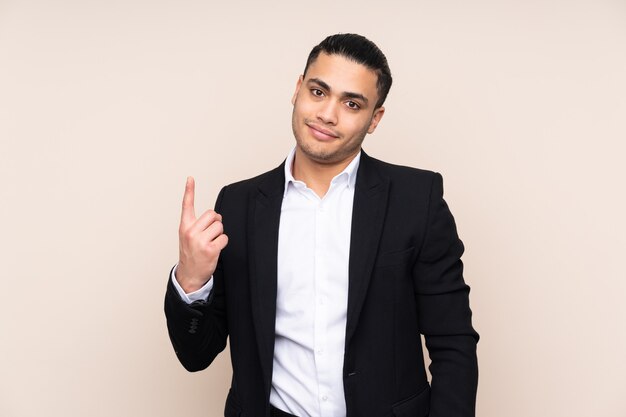 Asian business man isolated on beige wall pointing with the index finger a great idea