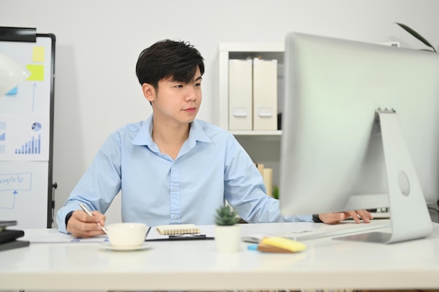 그의 직장에서 온라인 웨비나 교육을 보고 있는 컴퓨터 모니터를 보고 있는 아시아 사업가 관리자