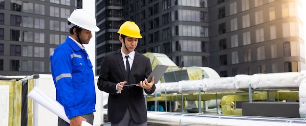 Asian business man and Office building owner and energy engineer plan a project to build a solar panel for the building under construction clean and green alternative energy concept