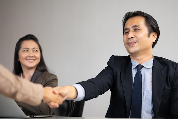 Uomo d'affari asiatico agitando le mani su un accordo di cooperazione commerciale imprenditori di successo handshake dopo buon affare