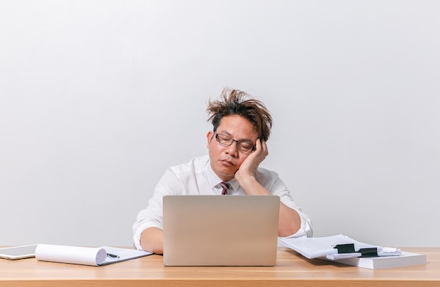 Uomo d'affari asiatico seduto e lavorando e stressato