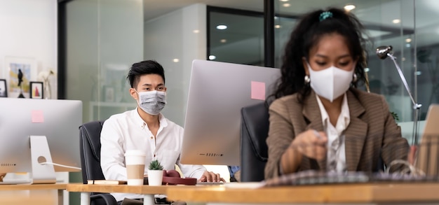 Asian business persons working in office wearing protective face mask