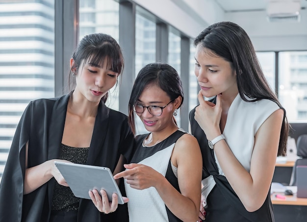 現代のオフィスでアジアのビジネス3人の女性がタブレットに見える