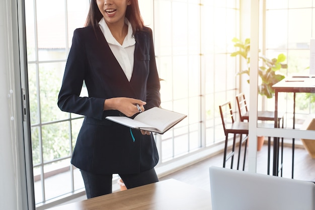 Asian business woman in formal suit taking note on notebook in meeting room at office.