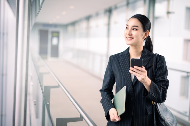 写真 笑顔、スマートなビジネス コンセプト、スマートなタブレットとスマート フォンを保持しているアジアのビジネス女性