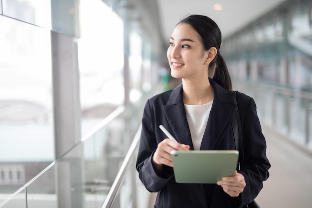 写真 アジア ビジネスの女性が離れて見て、スマート ビジネス コンセプトのタブレットを保持しています。