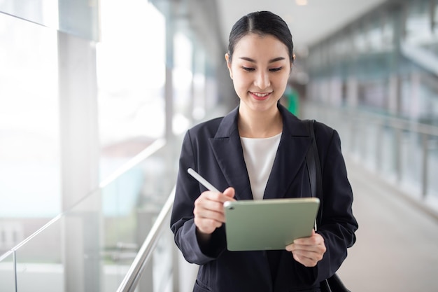 写真 アジア ビジネスの女性が離れて見て、スマート ビジネス コンセプトのタブレットを保持しています。