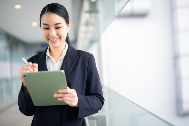 写真 アジア ビジネスの女性が離れて見て、スマート ビジネス コンセプトのタブレットを保持しています。