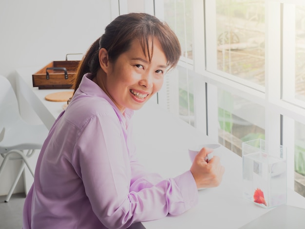 Asian business woman holding glass of coffee in Cafe with fish show case.