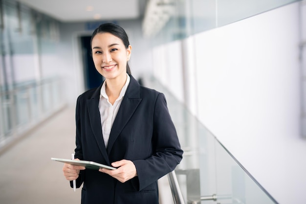 Asian business woman holding a tablet looking away , smart business concept.