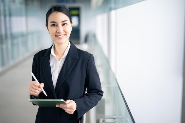 Photo asian business woman holding a tablet looking away , smart business concept.