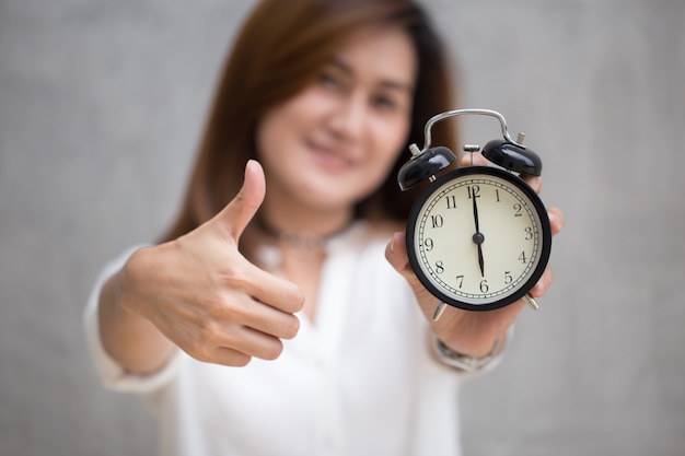 La manifestazione asiatica della donna di affari sfoglia su con un orologio per buon tempo o buon lavoro di finitura sul concetto di tempo