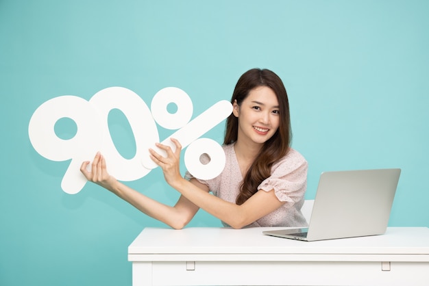 Asian business woman showing and holding 90 number and sitting with laptop