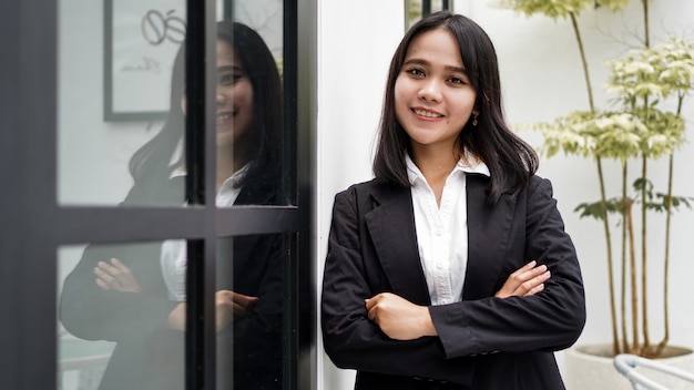 Donna asiatica di affari che sorride e che si leva in piedi nel front office