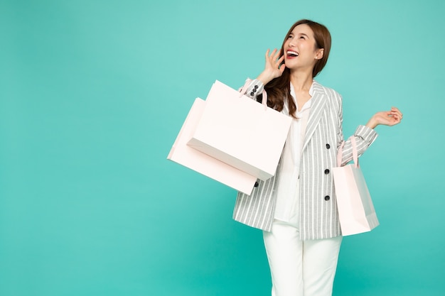 Photo asian business woman in suit holding light green shopping bags isolated on green background
