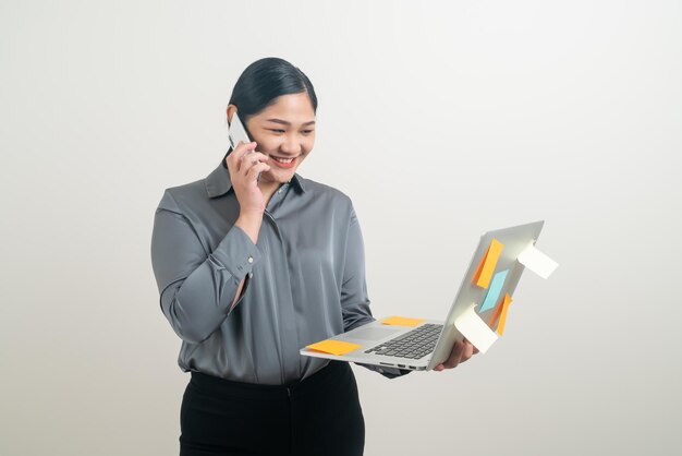 아시아 사업가 여성 이  ⁇  배경 에 노트북 을 들고 전화 를 하고 있다