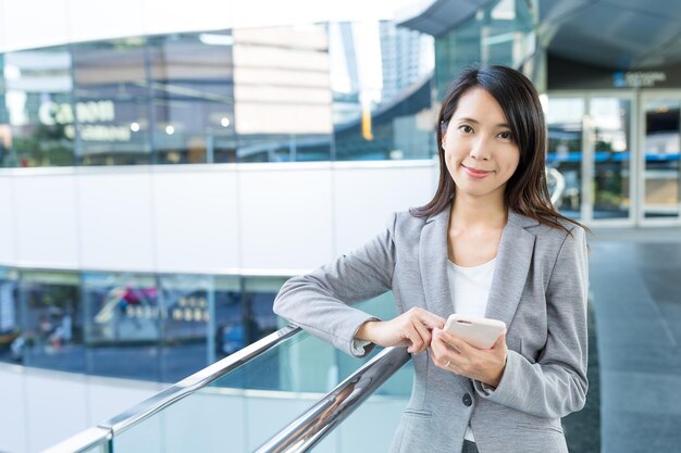 屋外でのアジア ビジネス女性の携帯電話の使用