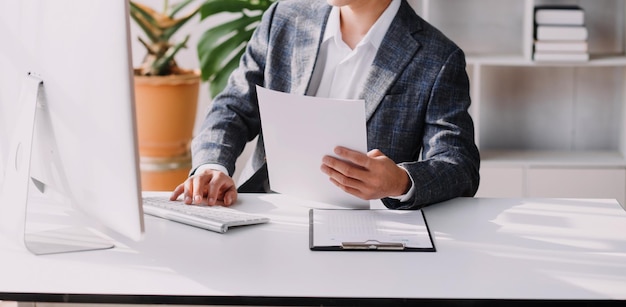 Asian Business woman using calculator and laptop for doing math finance on an office desk tax report accounting statistics and analytical research concept