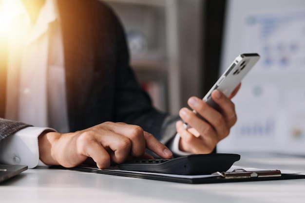 Asian Business woman using calculator and laptop for doing math finance on an office desk tax report accounting statistics and analytical research concept