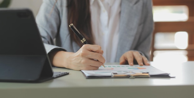 Asian Business woman using calculator and laptop for doing math finance on an office desk tax report accounting statistics and analytical research concept