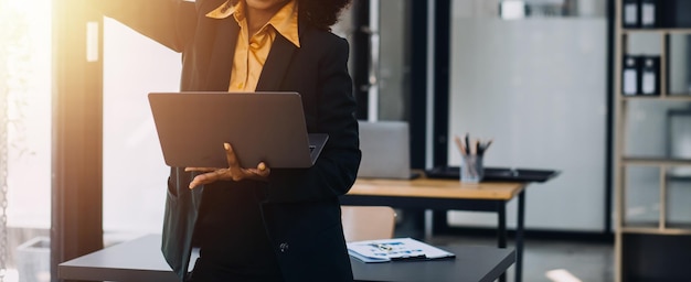 Asian Business woman using calculator and laptop for doing math finance on an office desk tax report accounting statistics and analytical research concept