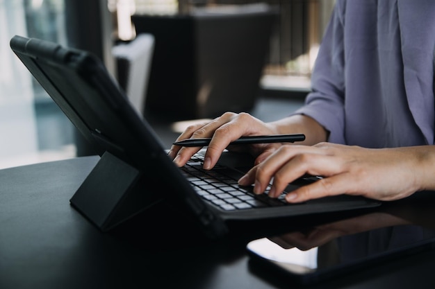 Asian Business woman using calculator and laptop for doing math finance on an office desk tax report accounting statistics and analytical research concept