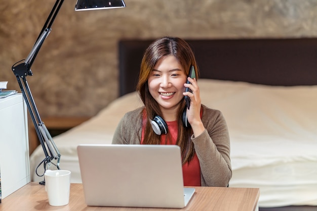 Asian business woman using technology laptop and working from home in bedroom