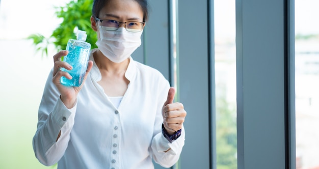 Asian business woman wearing protective mask with thumb up